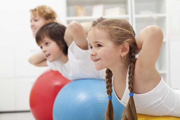Kids and woman doing exercises with balls