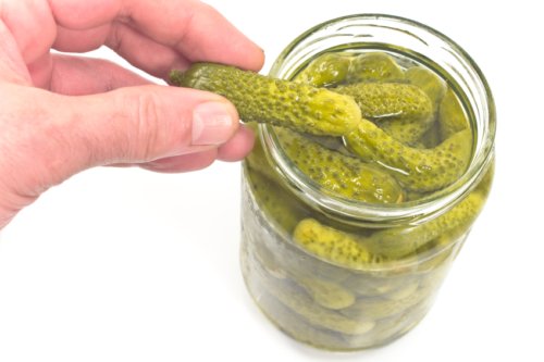 Pickled cucumbers in jar on white